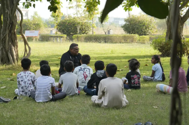 Children listening to a storyteller under the trees