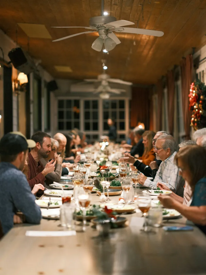 A community supper at a long table in a timber hall