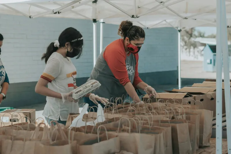 Volunteers packing paper bags of food for families